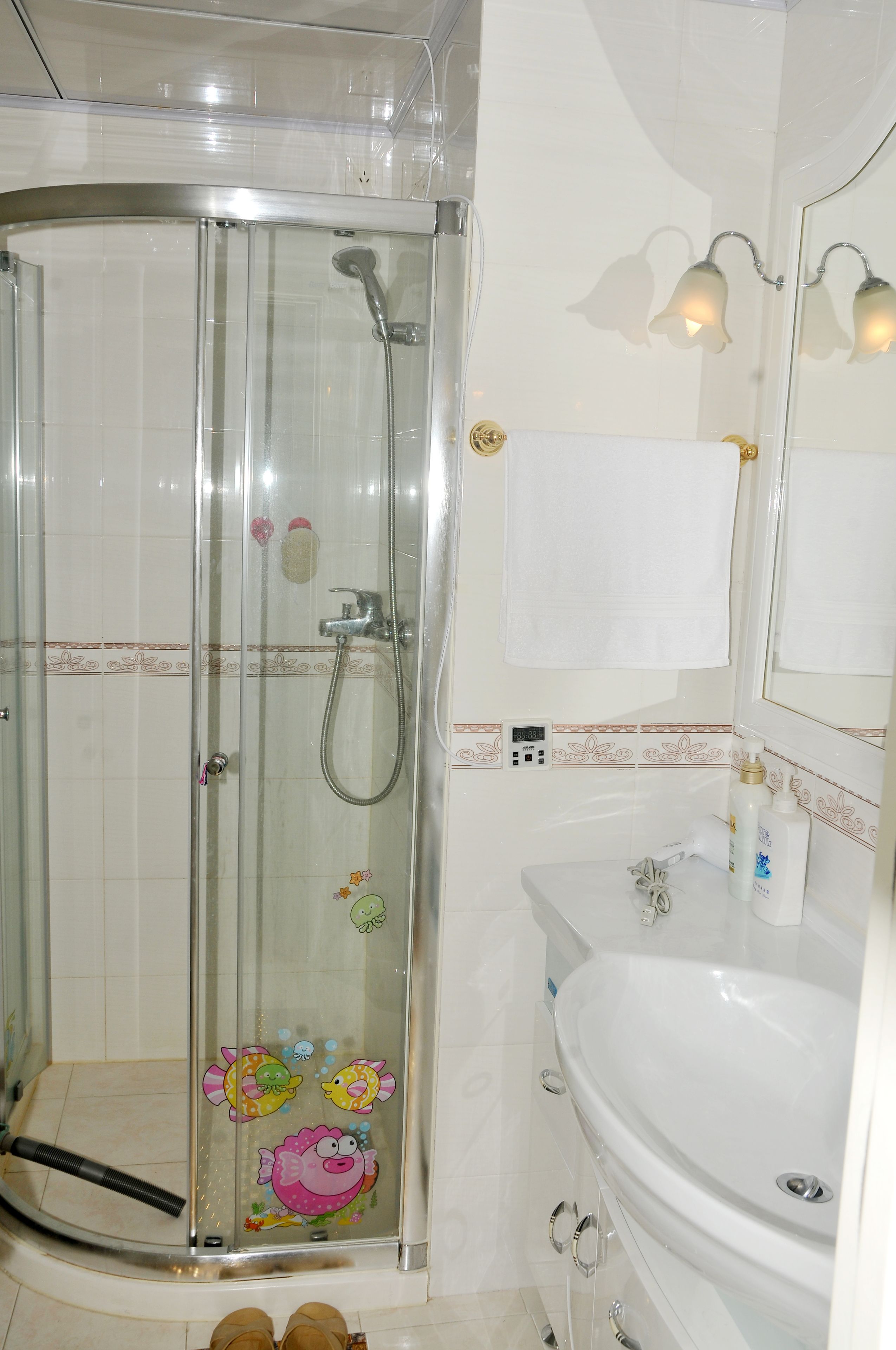 A bathroom with a glass-enclosed shower, a white sink, and a mirror with wall-mounted lights.