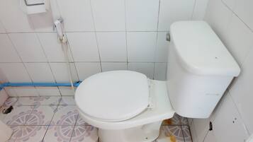 Un baño con inodoro, dispensador de papel higiénico y baldosas de suelo estampadas.
