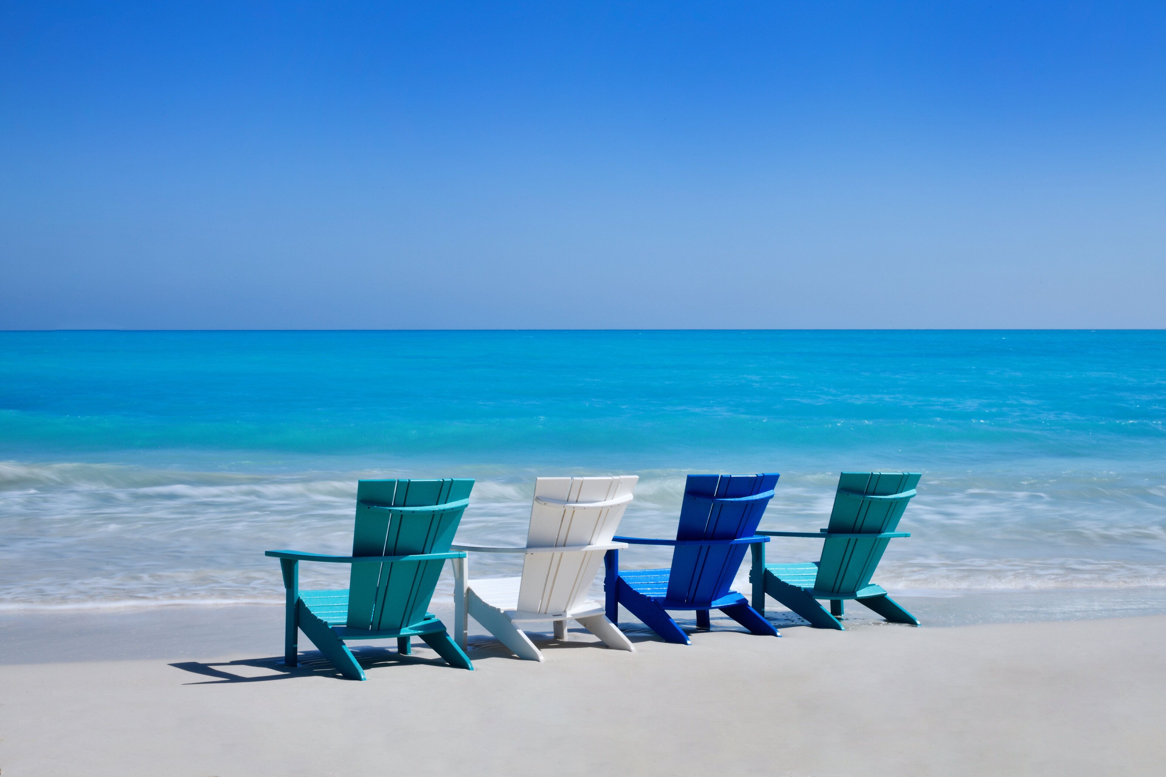 Three beach chairs facing the ocean.