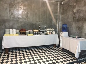 A room with a checkered floor, a table with plates and bowls, and a water dispenser.