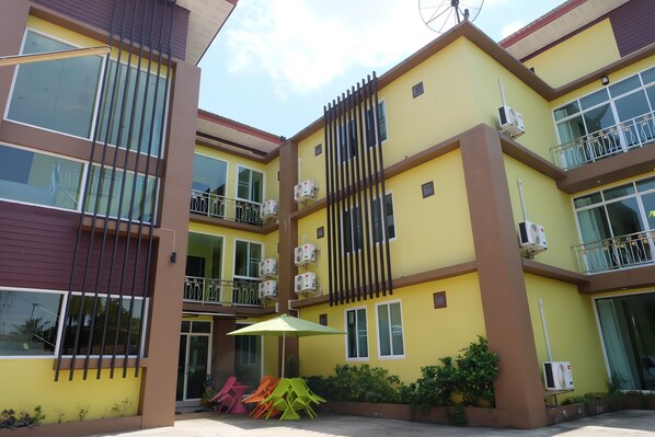 A multi-story building with balconies, air conditioning units, and a gated entrance.
