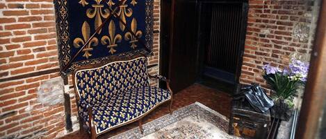 Una habitación tradicional con un sofá estampado, un adorno colgante y una pared de ladrillo.