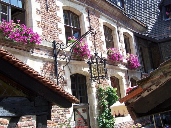 Un edificio histórico con paredes de ladrillo, ventanas arqueadas y macetas colgantes de flores.
