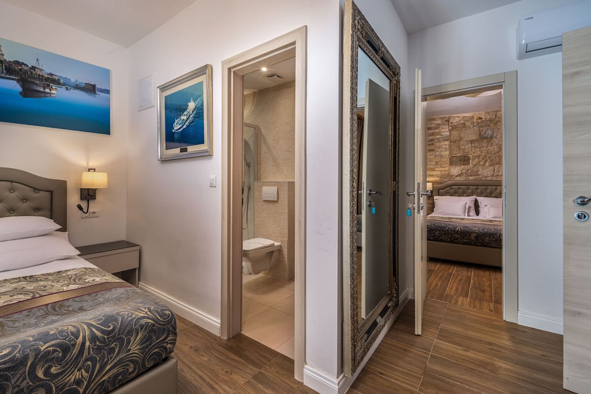 A bedroom with a bed, bedside table, lamp, and a painting on the wall.