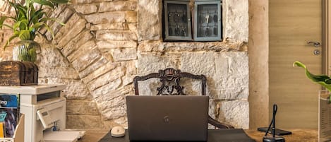 Un escriptori de fusta amb un ordinador portàtil, un ram de flors i un quadre amb un març de pedra.