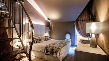 A bedroom with a bed, a nightstand, a lamp, a staircase, and a window with curtains.