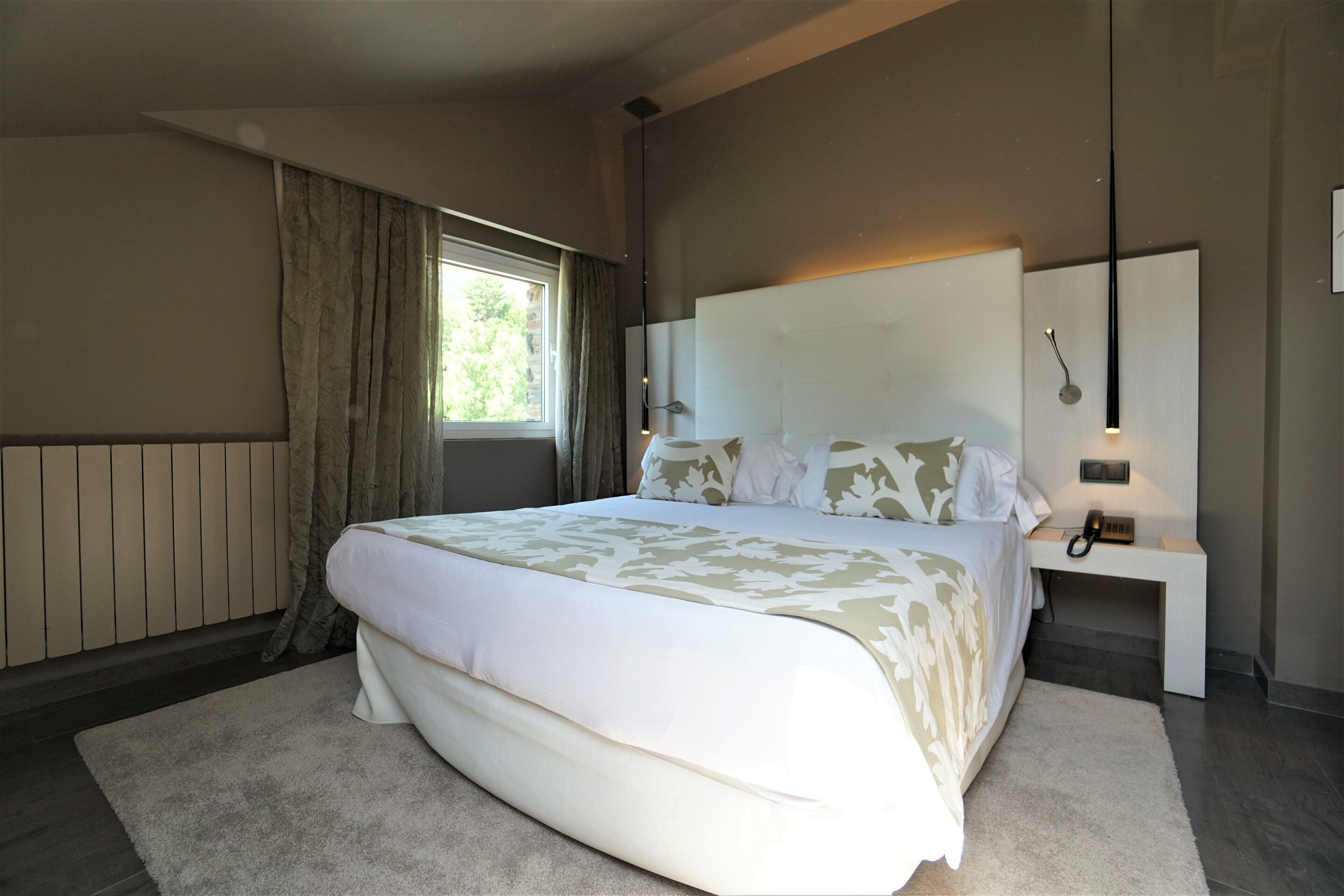 A modern bedroom with a large bed, a bedside table with a lamp, and a window with curtains.