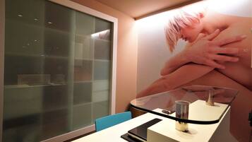 A modern room with a glass partition, a white desk, and a large poster on the wall.