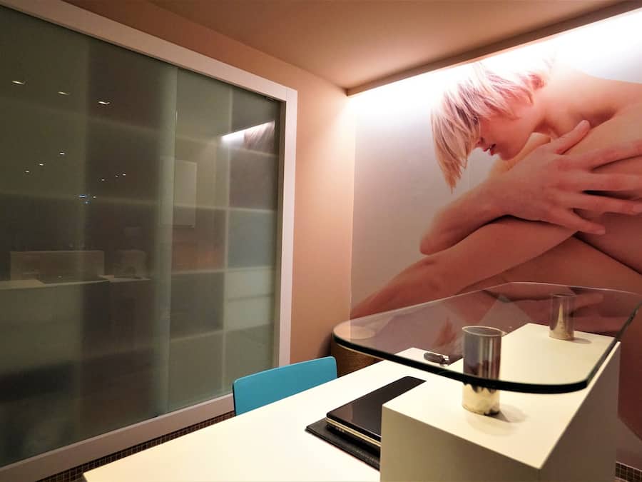 A modern room with a glass partition, a white desk, and a large poster on the wall.