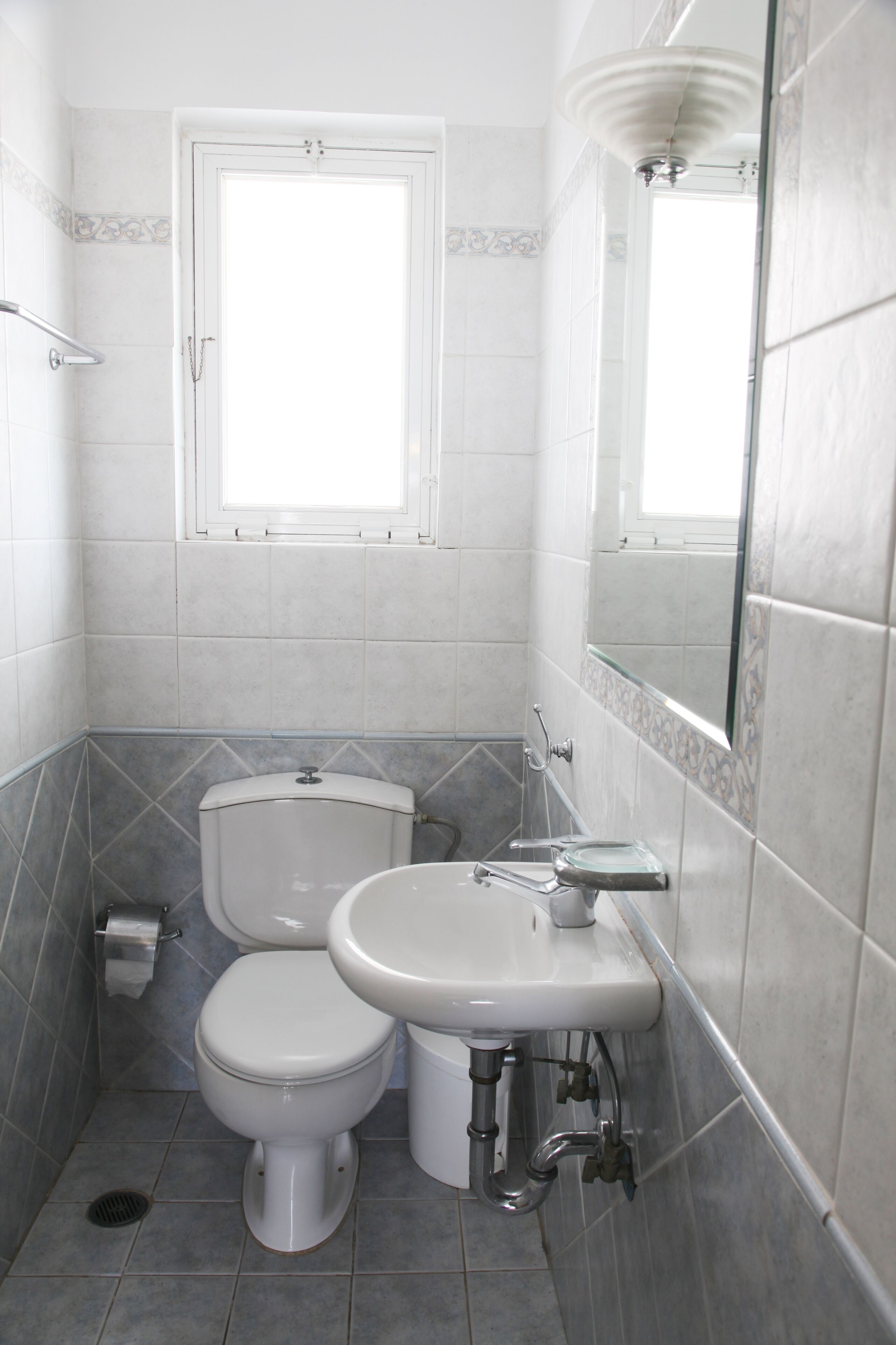A small bathroom with a toilet, sink, and a window.