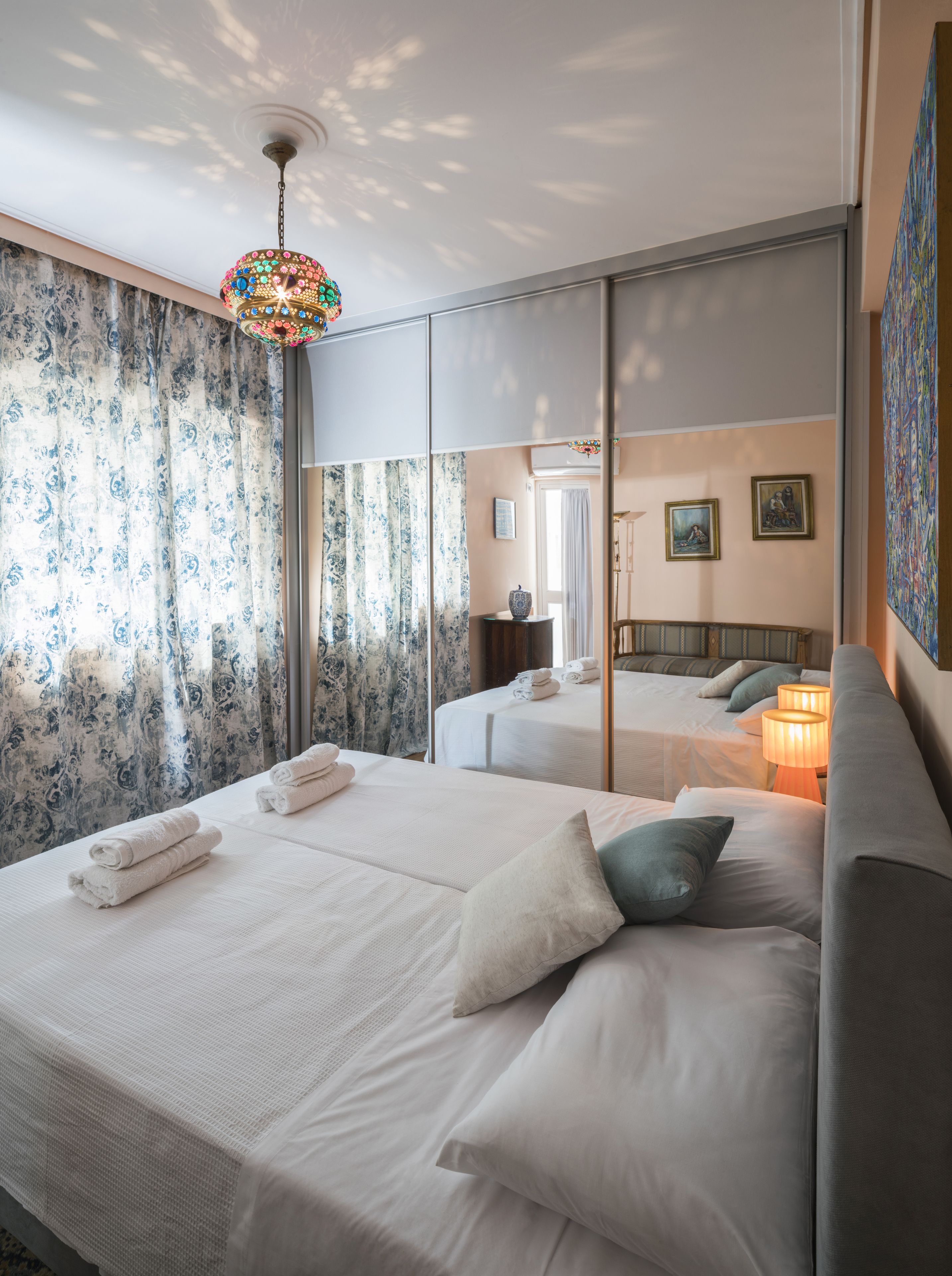 Ein Hotelzimmer mit zwei Betten, einem großen Spiegel und einer Kristallleuchter.