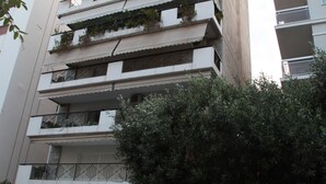 A multi-story building with balconies, a red convertible parked in front, and a no parking sign visible. - Unique flat with sea view (Palaio Faliro)