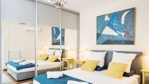 A modern hotel room with a large bed, a mirror, a painting, and a chandelier. - Unique flat with sea view (Palaio Faliro)