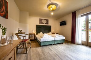 Ein Hotelzimmer mit Bett, Schreibtisch, Stuhl, Fernseher und einem Fenster mit Vorhängen.