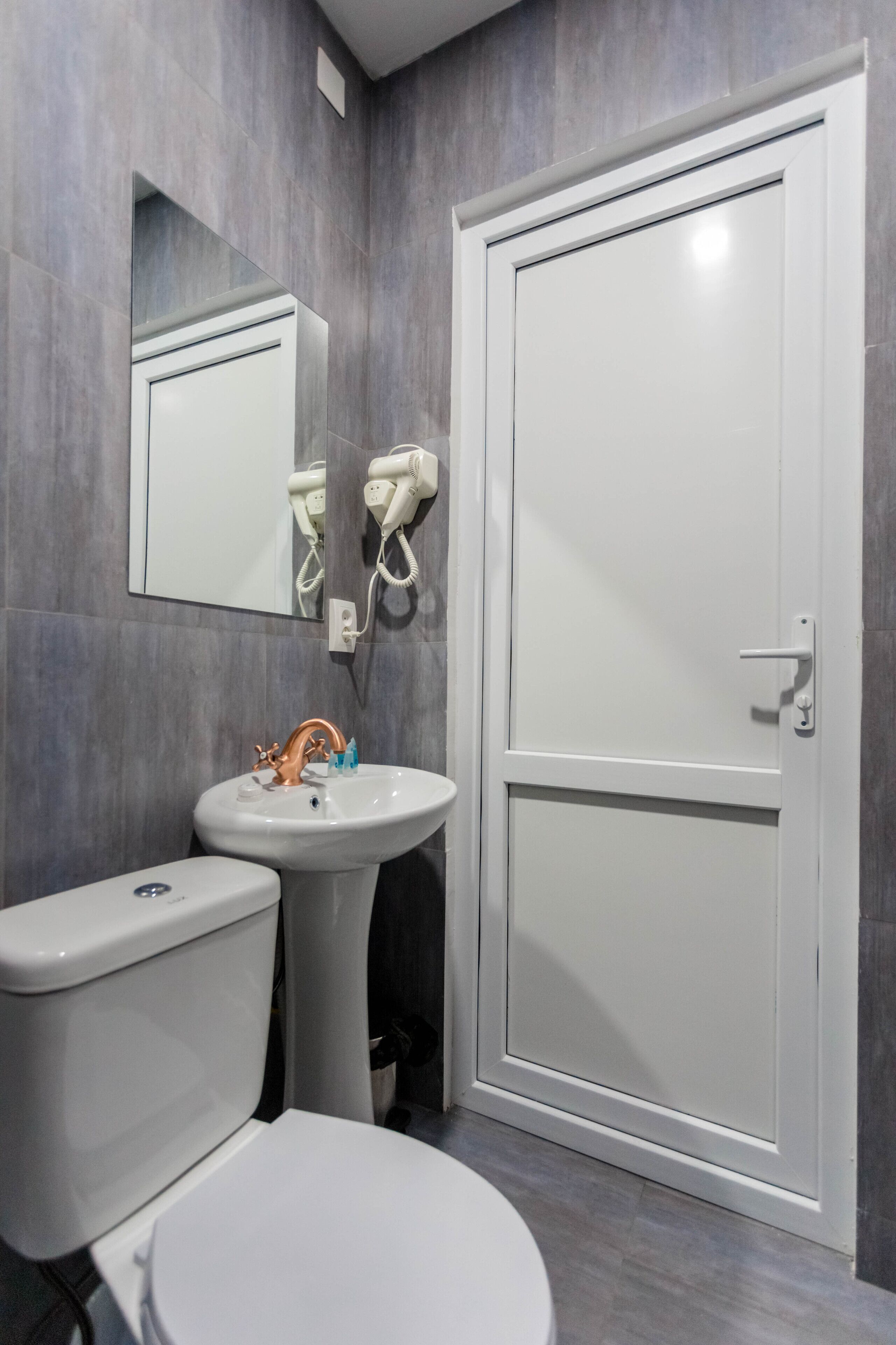 A bathroom with a white toilet, a pedestal sink, and a white door.