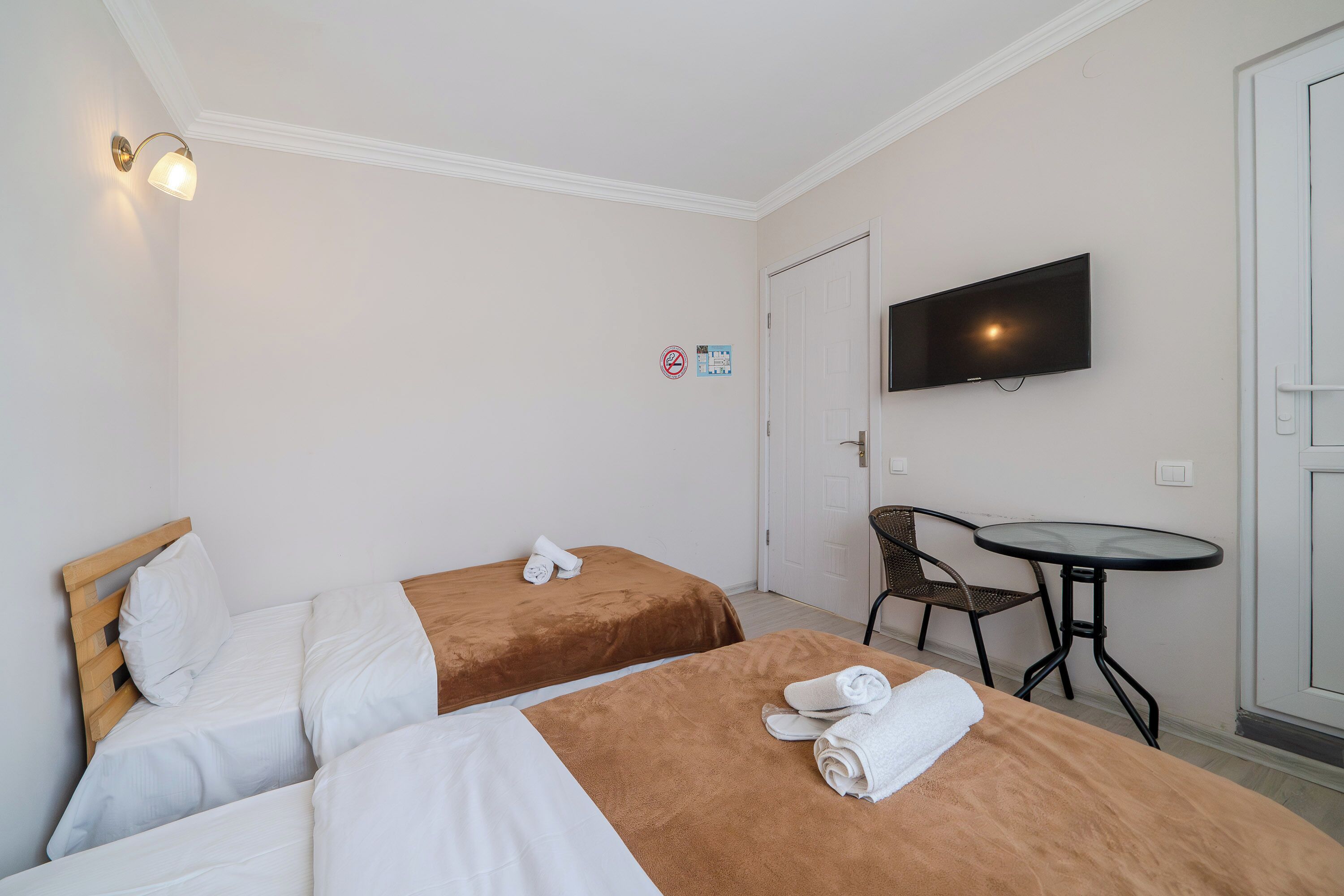 A hotel room with two beds, a TV, a small table, and a chair.