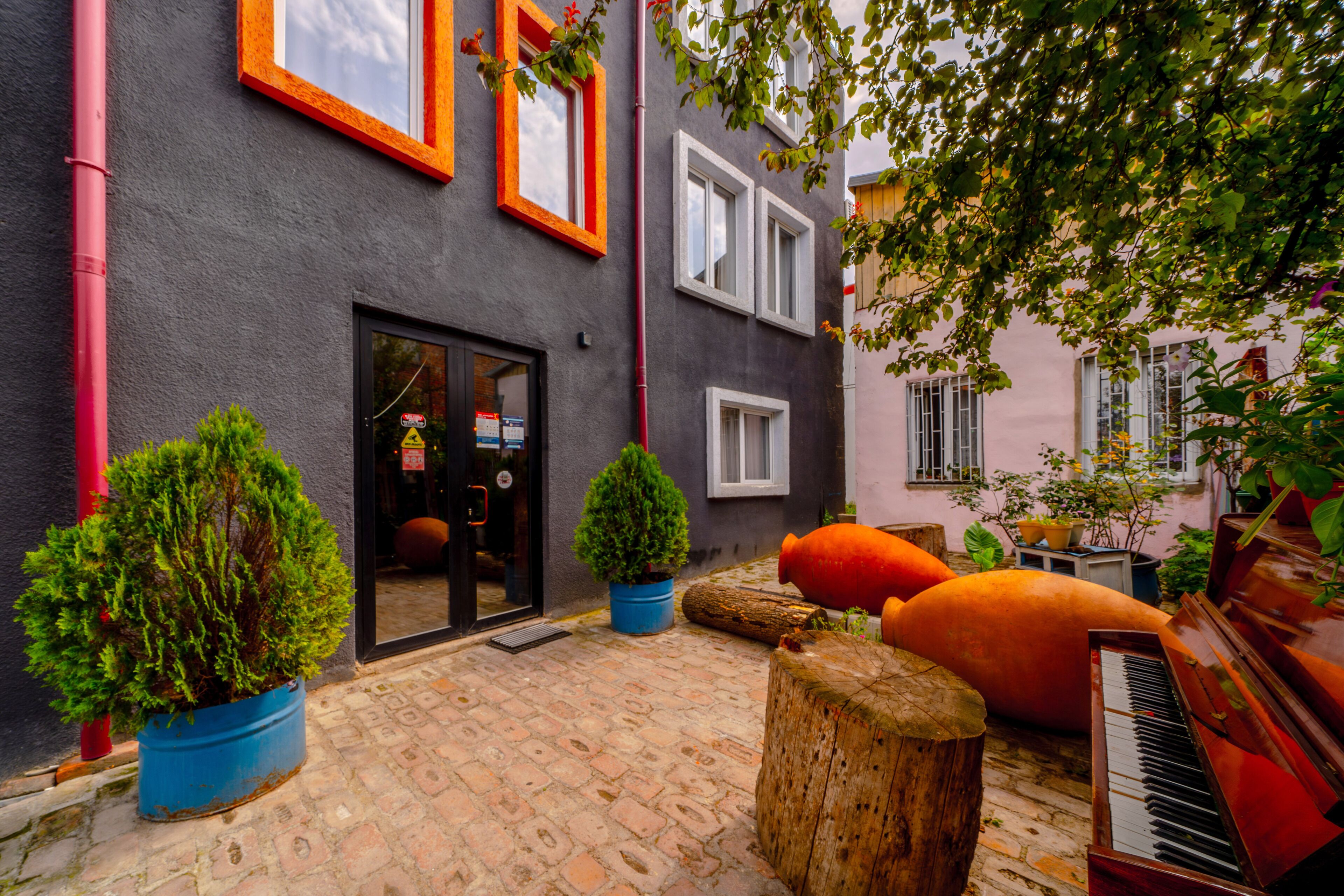 A courtyard with a piano, potted plants, and a door with a glass panel.