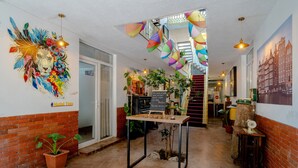 A hotel lobby with a mural, a staircase, and a reception desk. - Hotel TATO (Tbilisi)