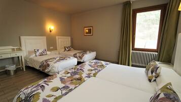 A hotel room with two beds, a desk, and a window with curtains.