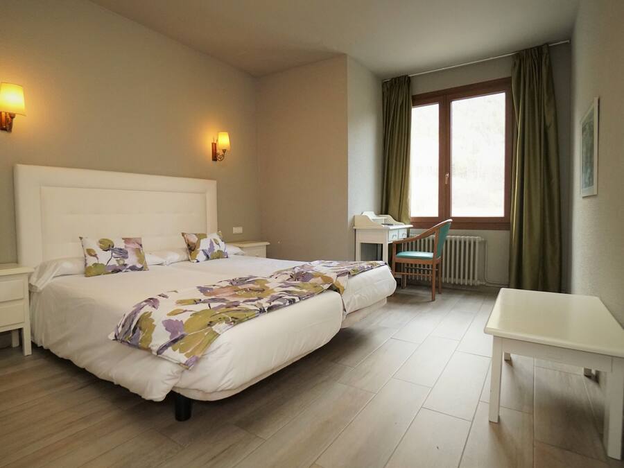 A hotel room with a large bed, bedside tables, a desk, and a chair.