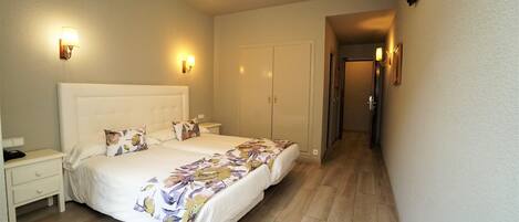 A bedroom with a large bed, bedside tables, a wardrobe, and a TV mounted on the wall.
