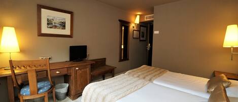 A hotel room with a bed, desk, chair, and a television.