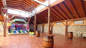 Un espace intérieur doté d’un haut plafond en bois, de murs en pierre et d’un espace de jeux coloré.