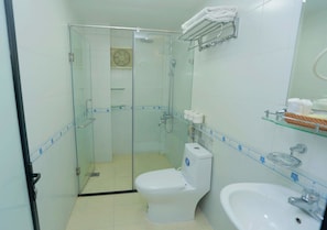 Un baño pequeño con ducha de vidrio, inodoro y lavamanos.