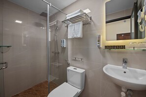 Un baño moderno con ducha de vidrio, inodoro, lavabo y toallero.