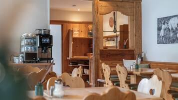 A rustic wooden interior with a coffee machine, wooden chairs, and a dining table.