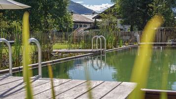 A wooden deck with a pool, surrounded by a wooden fence and greenery.