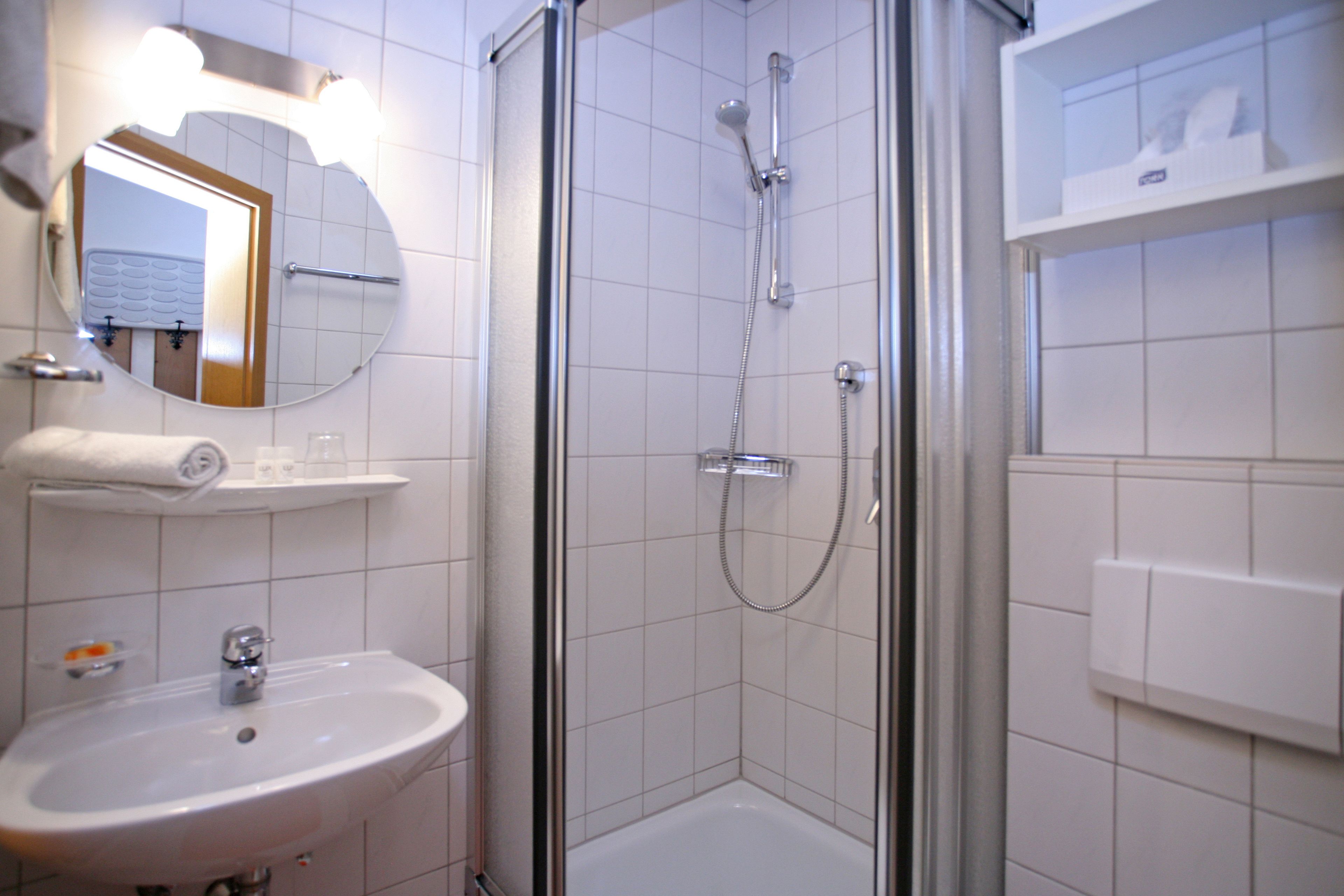 Ein Badezimmer mit Duschkabine, Waschbecken und Spiegel.