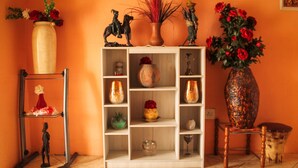 A room with a wooden shelving unit displaying various decorative items, including vases and figurines. - RIO GUEST HOUSE LS (Maseru)