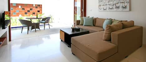 Uma sala de estar moderna com um sofá seccional bege, uma mesa de centro e uma área de jantar com mesa e cadeiras.