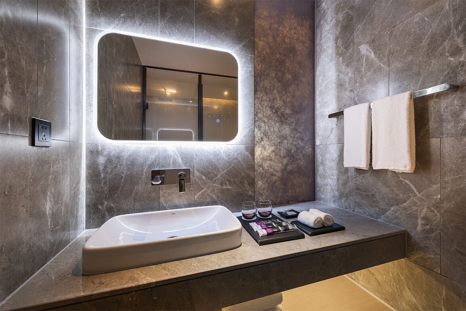 A modern bathroom with a large sink, a mirror, and a towel rack.