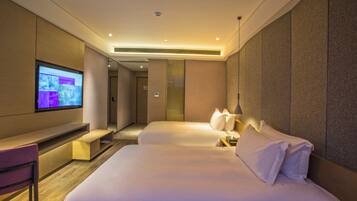 A hotel room with two beds, a TV, a desk, and a chair.