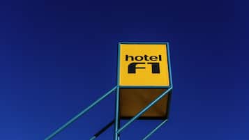 Ein gelbes Schild mit dem Schriftzug 'hotel F1' vor blauem Himmel.