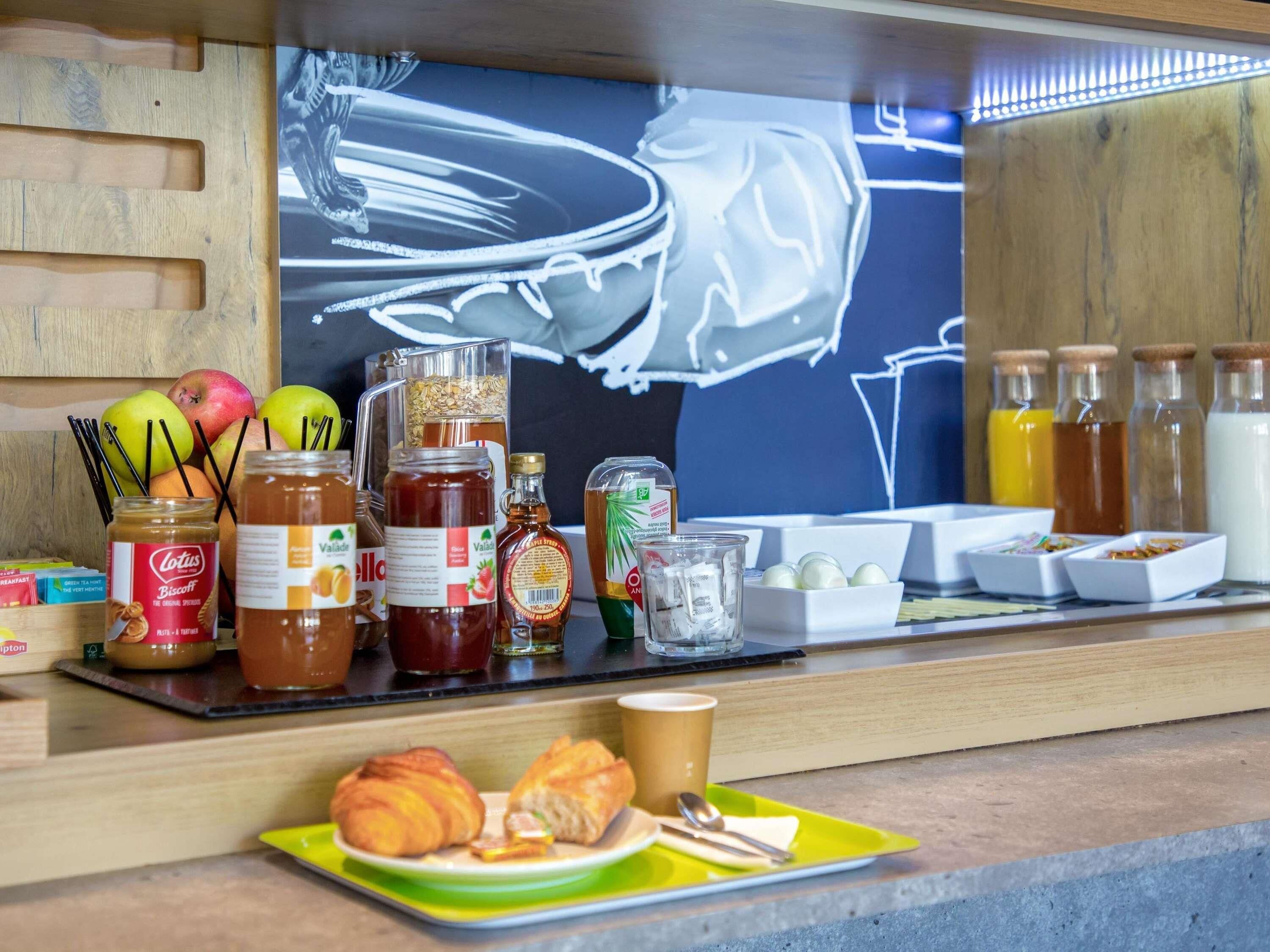 Un bufé de desayuno con diversos alimentos, como pastelería, frutas y salsas.