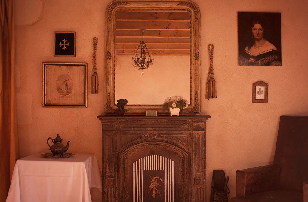 Een kamer met een open haard, een spiegel en ingelijste foto's aan de muur.