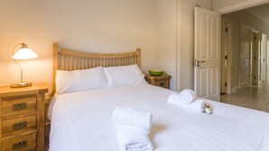 A neatly made bed with white linens, a wooden headboard, a bedside table with a lamp, and a bowl. - Dublin Airport Park north (Dublin)