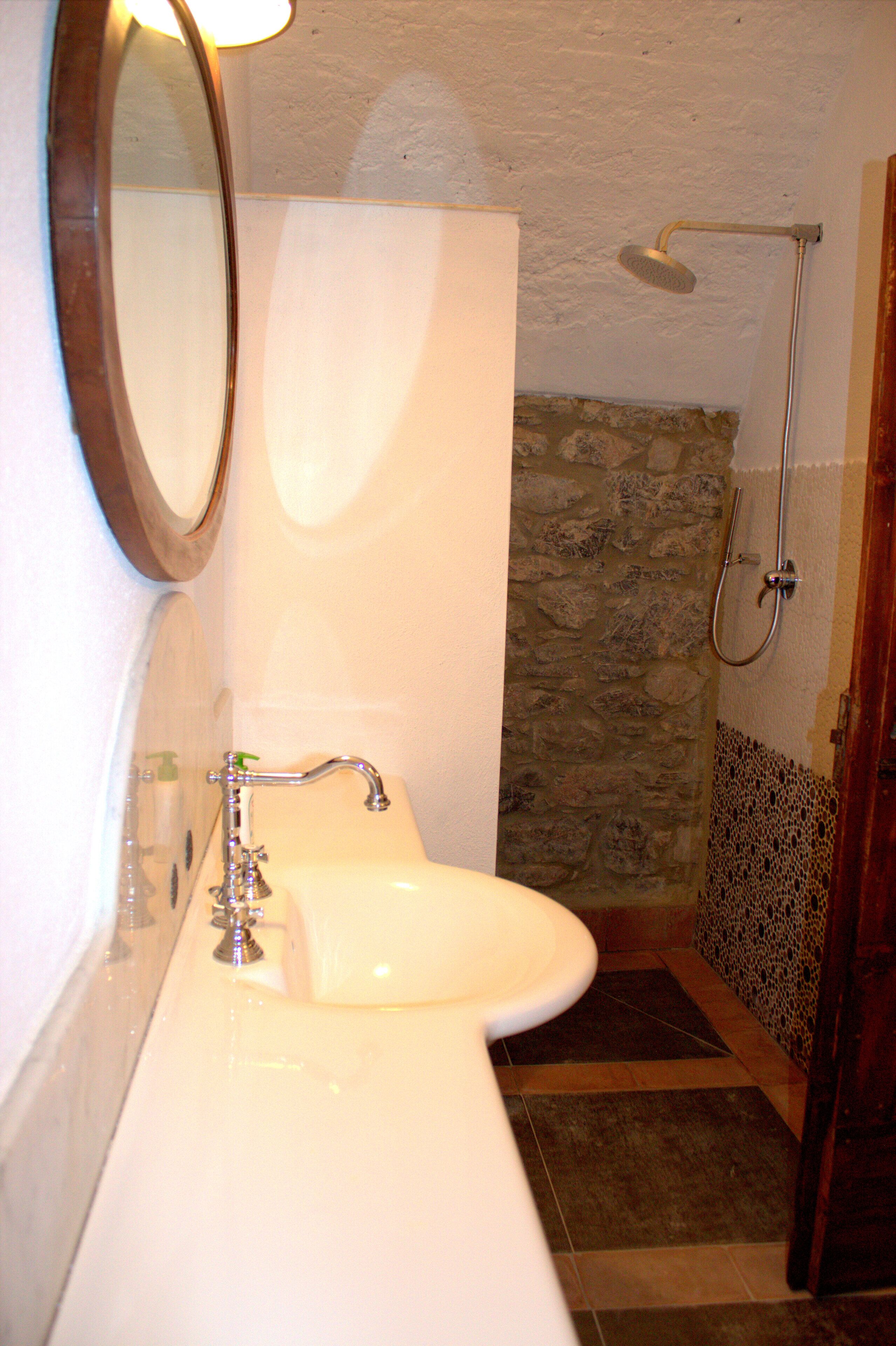 A bathroom with a white sink, a mirror, and a shower.