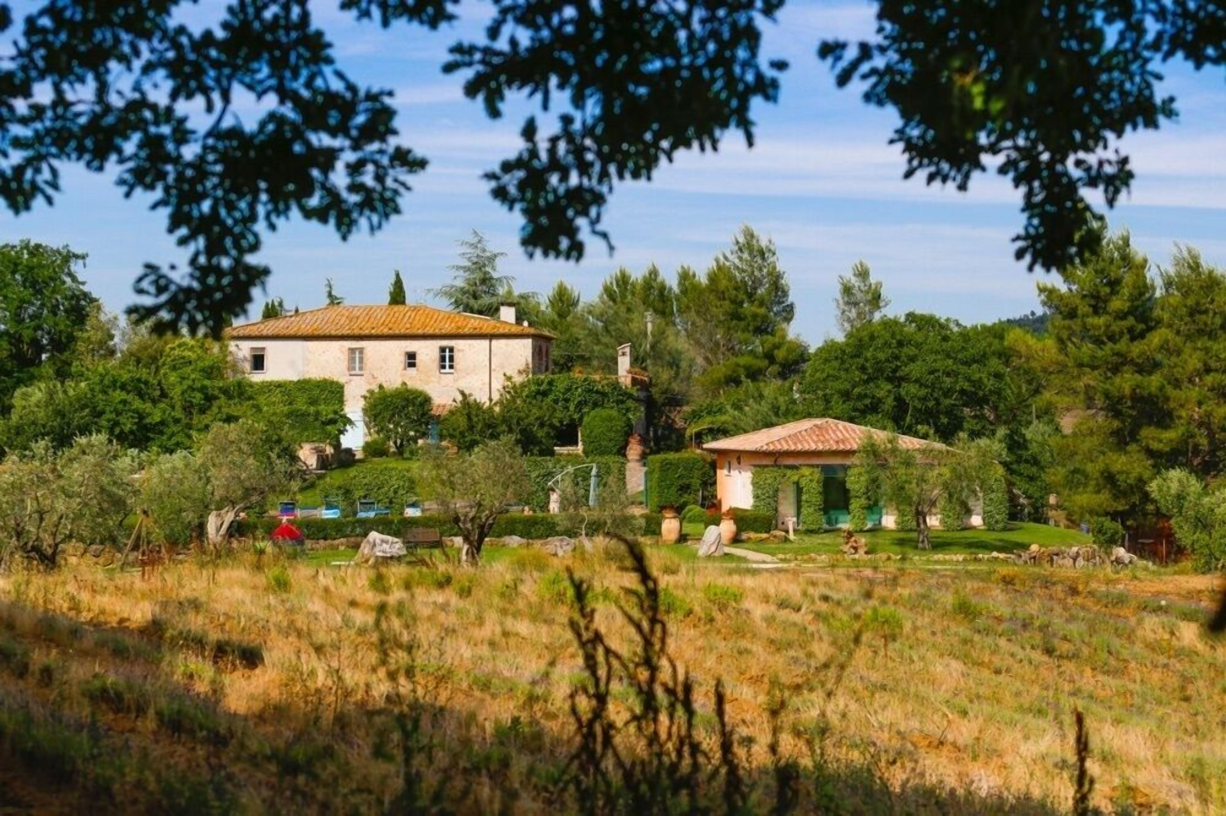 A large house with a tiled roof, surrounded by lush greenery and trees.