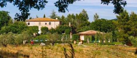 A large house with a tiled roof, surrounded by lush greenery and trees.