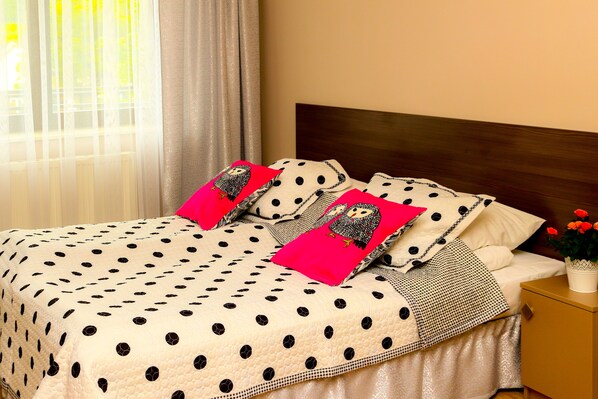 A bed with a polka dot bedspread, two pillows with an owl design, and a nightstand with a potted plant. - JANDA Resort & Conference (Mszana Dolna)