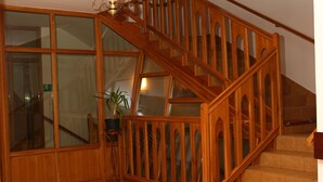 A wooden staircase with glass panels, a potted plant, and a tiled floor. - JANDA Resort & Conference (Mszana Dolna)
