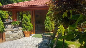 A patio area with stone flooring, a wooden pergola, and potted plants. - JANDA Resort & Conference (Mszana Dolna)