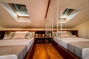 Una habitación con dos camas, suelo de madera y tragaluces.