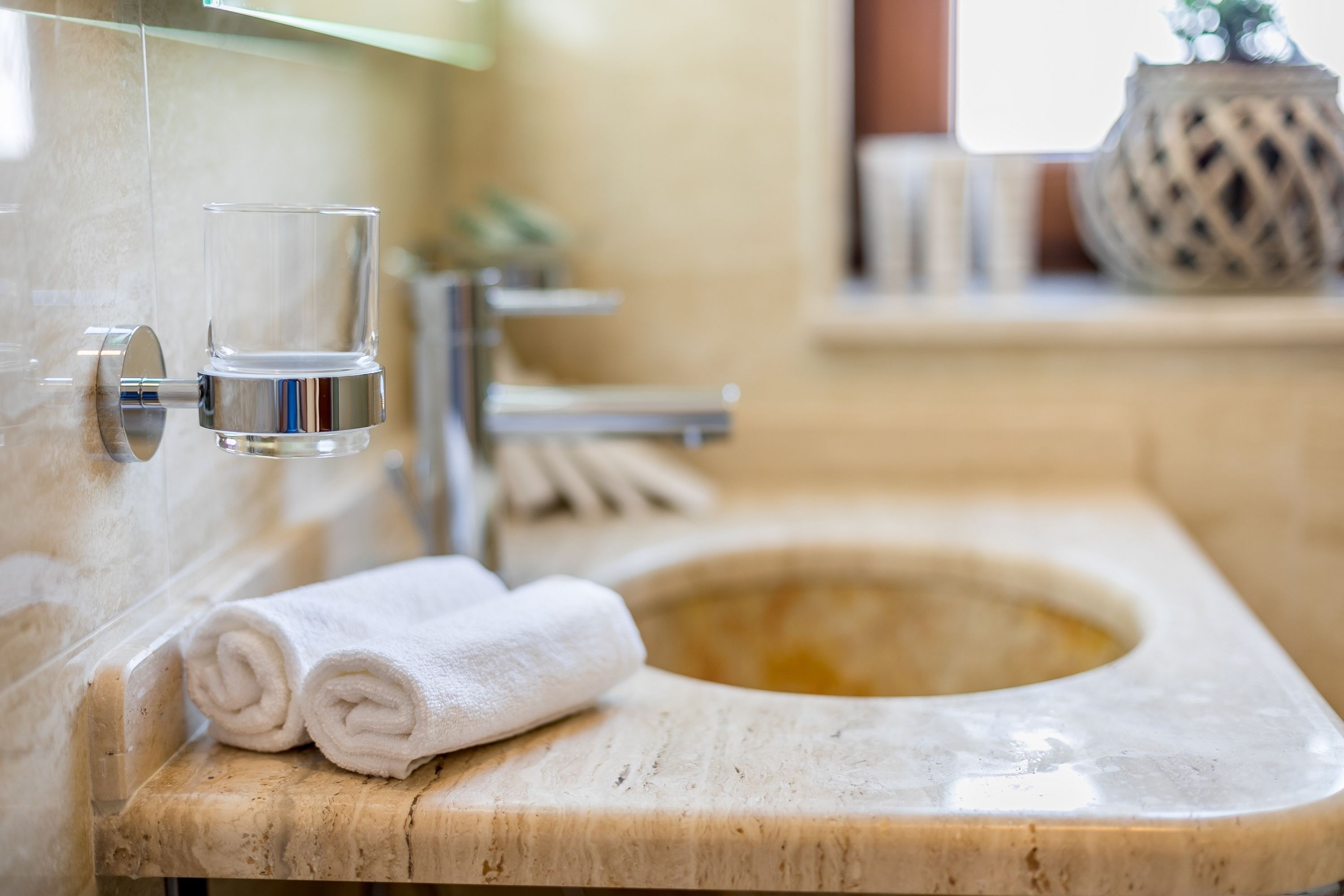 Une salle de bain avec un lavabo en marbre, un verre et une serviette.