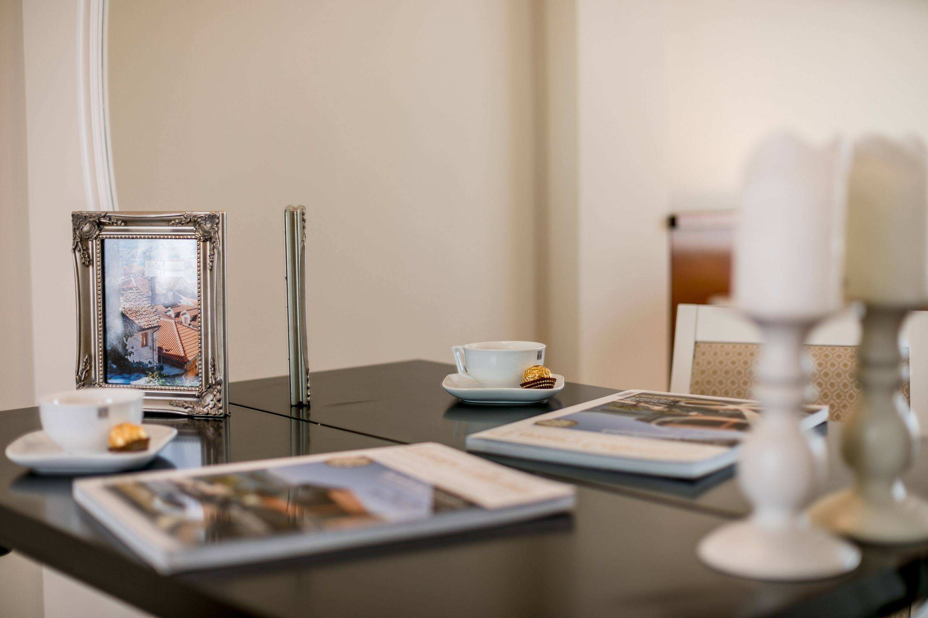 Ein Tisch mit einem gerahmten Foto, einer Tasse Tee, einer Kerze und ein paar Zeitschriften.