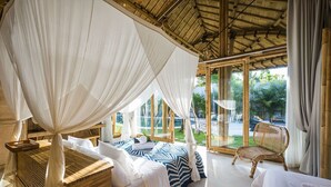 Una habitación con cama a dosel, una silla aparte y vistas al jardín.